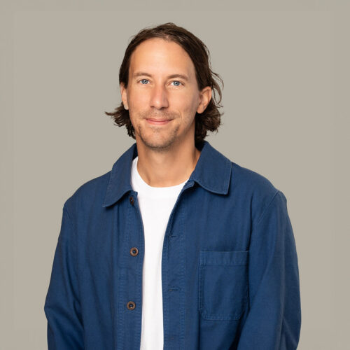 Picture of Nicholas wearing a white t-shirt under a blue denim shirt